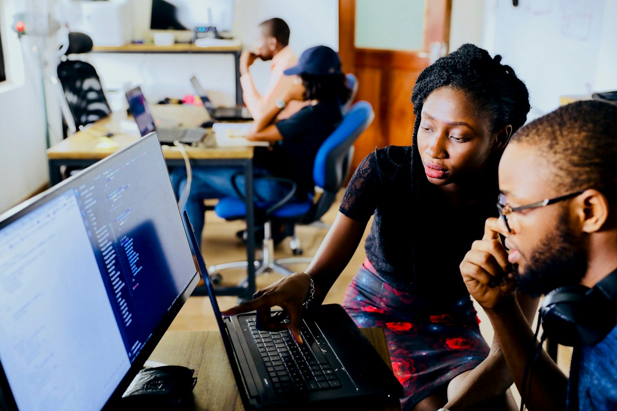 Developers collaborating over code on a monitor.